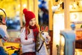 Kids at Christmas fair. Child at traditional street Xmas market in Germany. Winter outdoor fun. Little girl in knitted hat riding