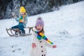 Kids in colorful clothes playing with snow outdoors during snowfall. Active leisure with children in winter on cold days Royalty Free Stock Photo