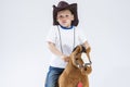 Kids Consepts. Portrait of Caucasian Little Boy in Cowboy Clothing Making Fases Posing With Symbolic Plush Horse Against White. Royalty Free Stock Photo