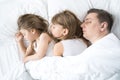 Kids, dad sleep together in bed on pillows under blanket. Family joint sleeping. Father with cute little daughters. Insomnia, Royalty Free Stock Photo