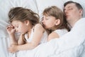 Kids, dad sleep together in bed on pillows under blanket. Family joint sleeping. Father with cute little daughters. Insomnia, Royalty Free Stock Photo