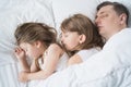 Kids, dad sleep together in bed on pillows under blanket. Family joint sleeping. Father with cute little daughters. Insomnia, Royalty Free Stock Photo
