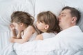 Kids, dad sleep together in bed on pillows under blanket. Family joint sleeping. Father with cute little daughters. Insomnia, Royalty Free Stock Photo