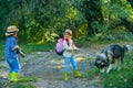 Kids with dog walking away. A little blond girl and cute boy with her pet dog outdooors in park.