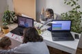 Kids doing homework and mother working online in one room, distant education at home Royalty Free Stock Photo