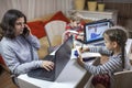 Kids doing homework and mother working online in one room, distant education at home