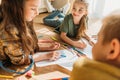 Kids drawing on paper with pencils while lying on floor