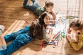 Kids drawing on paper with pencils while lying on floor