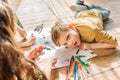 Kids drawing on paper with pencils while lying on floor