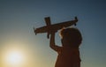 Kids dreams. Boy pilot with toy airplane, silhouette. Child playing outdoors. Happy childhood. Daydreaming.