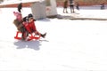 Kids driving a sledges over a snow capped slope. Children have fun.