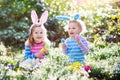 Kids on Easter egg hunt in blooming spring garden