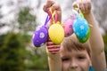 Kids on Easter egg hunt in blooming spring garden. Children searching for colorful eggs in flower meadow. Toddler boy and his brot