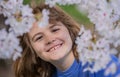 Kids face with flower on the Spring. Child in blooming cherry garden on beautiful spring day. Happy child during spring Royalty Free Stock Photo