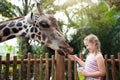 Kids feed giraffe at zoo. Children at safari park Royalty Free Stock Photo