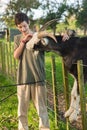 kids feeding a goat on green grass in a farmyard or on a lawn, countryside or village environment, contact zoo or