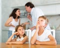 Kids feels upset while parents quarrel at background. Little girl and boy frustrated with psychological problem caused Royalty Free Stock Photo