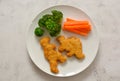 Kids food. nuggets with vegetables. Dinosaur shaped chicken, fish or turkey nuggets, ready to eat Royalty Free Stock Photo