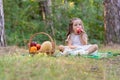 Kids forest picnic. Child with basket of autumn fruits eating apple. Toddler kid in sunny park. Little girl enjoying