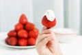 Kids hand is holading red ripe jucy strawberry with sour cream at plate of many berries background on table in light