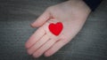 Kids hand holding a heart over wooden background in a conceptual image of love, family and care Royalty Free Stock Photo