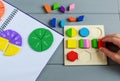 Kids hand moves colorful math fractions on gray wooden background or table. Interesting creative funny math for kids. Education