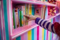 kids hand pulling a book from a candystriped shelf Royalty Free Stock Photo