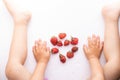 Kids hands and legs near ugly strawberries on white background, top view and copy space