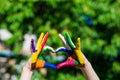 Kids hands painted in bright colors make a heart shape on summer nature background Royalty Free Stock Photo