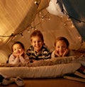 Kids, happy and playing in blanket fort with portrait for fantasy, bonding and fairy lights at night. Friends, children Royalty Free Stock Photo