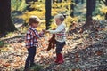 Kids harvest grass in autumn forest. Brother and sister play on fresh air. Small boy and girl friends have fun in woods
