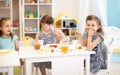 Kids have a lunch in daycare centre. Children eating healthy food in kindergarten. Little girl have fun showing mustache Royalty Free Stock Photo