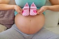 Kids have small feet that leave big footprints. Closeup shot of a pregnant woman holding a pair of pink baby shoes Royalty Free Stock Photo