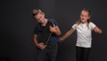 Kids are having fun on black background. Boy plays on the panelboard, as on the hyitar. Girl next to her dances