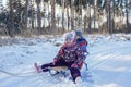 Kids having fun and riding the sledge in winter snowy forest, enjoy seasonal outdoor activities Royalty Free Stock Photo