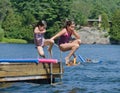 Kids having summer fun jumping off dock into lake Royalty Free Stock Photo