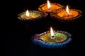 Four burning colorful candles indian style for Diwali celebration. Black background.
