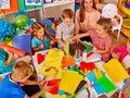 Kids holding colored paper and glue on table in