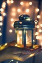 Kids holds Christmas lantern in hands on lights bokeh background.