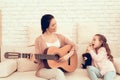 Mom with Guitar in Hand and Girl Sitting on Carpet Royalty Free Stock Photo