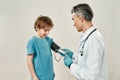 Kids in hospital. Professional mature doctor pediatrician in medical uniform and sterile gloves measuring blood pressure