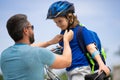 Kids insurance. Father and son concept. Father teaching son riding bike. Father helping his son to wear a cycling helmet