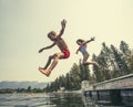 Kids jumping off the dock into a beautiful mountain lake Royalty Free Stock Photo