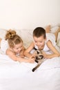 Kids laying in bed playing with their kitten Royalty Free Stock Photo