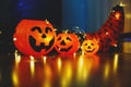 Kids legs in bright colorful striped funny socks in garland lights on floor with pumpkins in room.