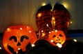 Kids legs in stylish warm bright colorful striped funny socks in garland lights on floor with pumpkins in room.