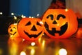 Kids legs in stylish warm bright colorful striped funny socks in garland lights on floor with pumpkins in room.