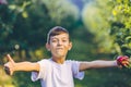 Joyous boy with fresh apple, giving thumb up with satisfaction. Royalty Free Stock Photo