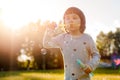 Kids little girl blowing bubbles on the Playground with sunset background Royalty Free Stock Photo