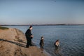 Kids and mom running in water on river bank in autumn. Boy is drinking river water. Disobedience. Happy family on the Royalty Free Stock Photo